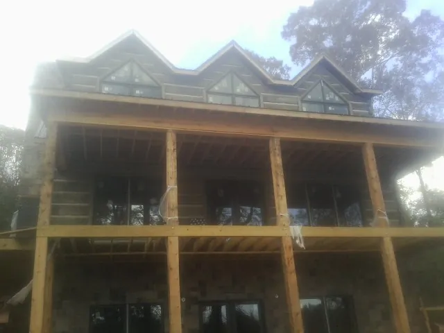 Dormers and porch framing on a large log home under construction — Roof Coating work by our crew in Woodstock Valley