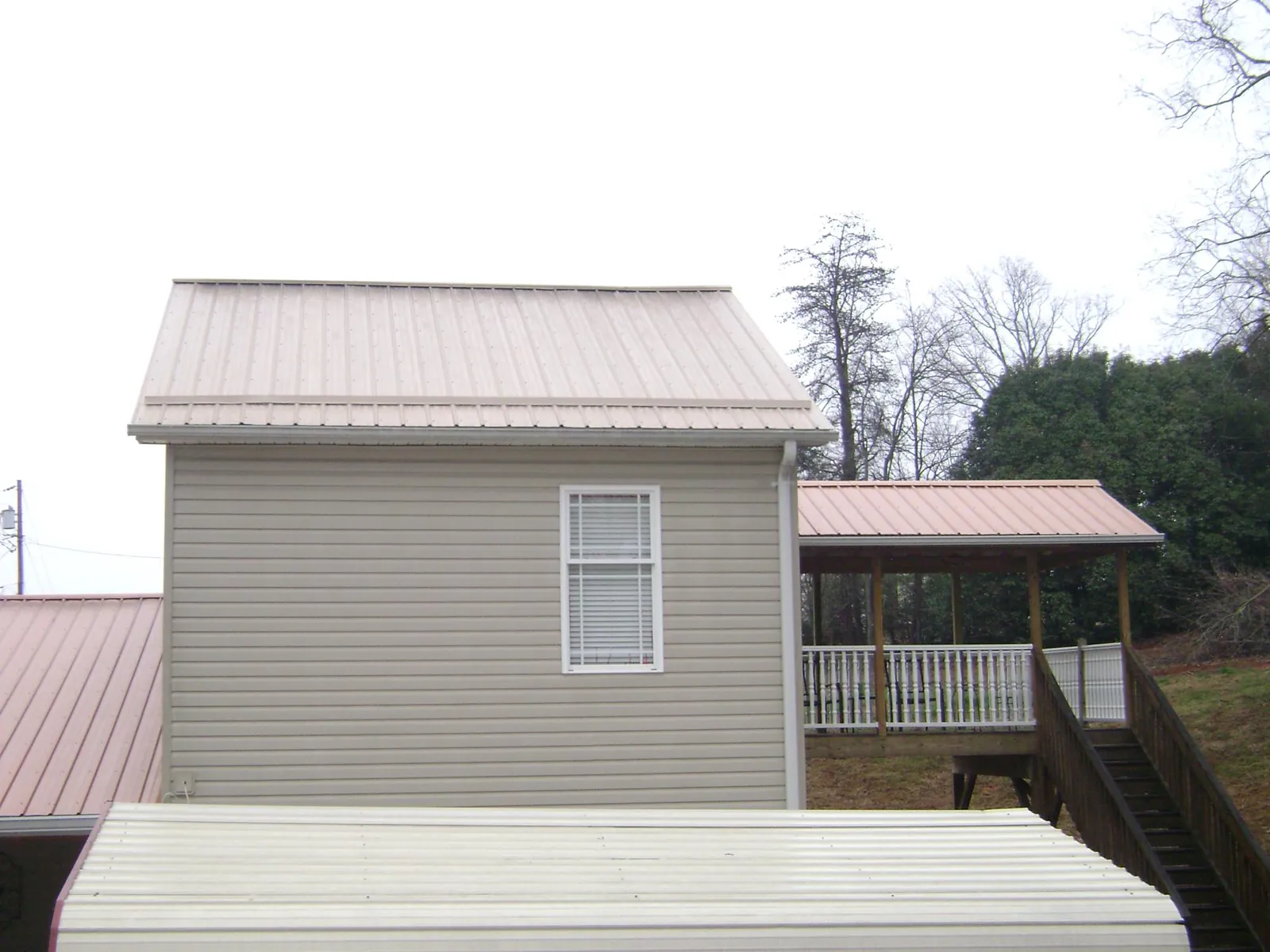 Tan metal roofs on a two story addition and attached porch, from a Roof Replacement job in Woodstock Valley