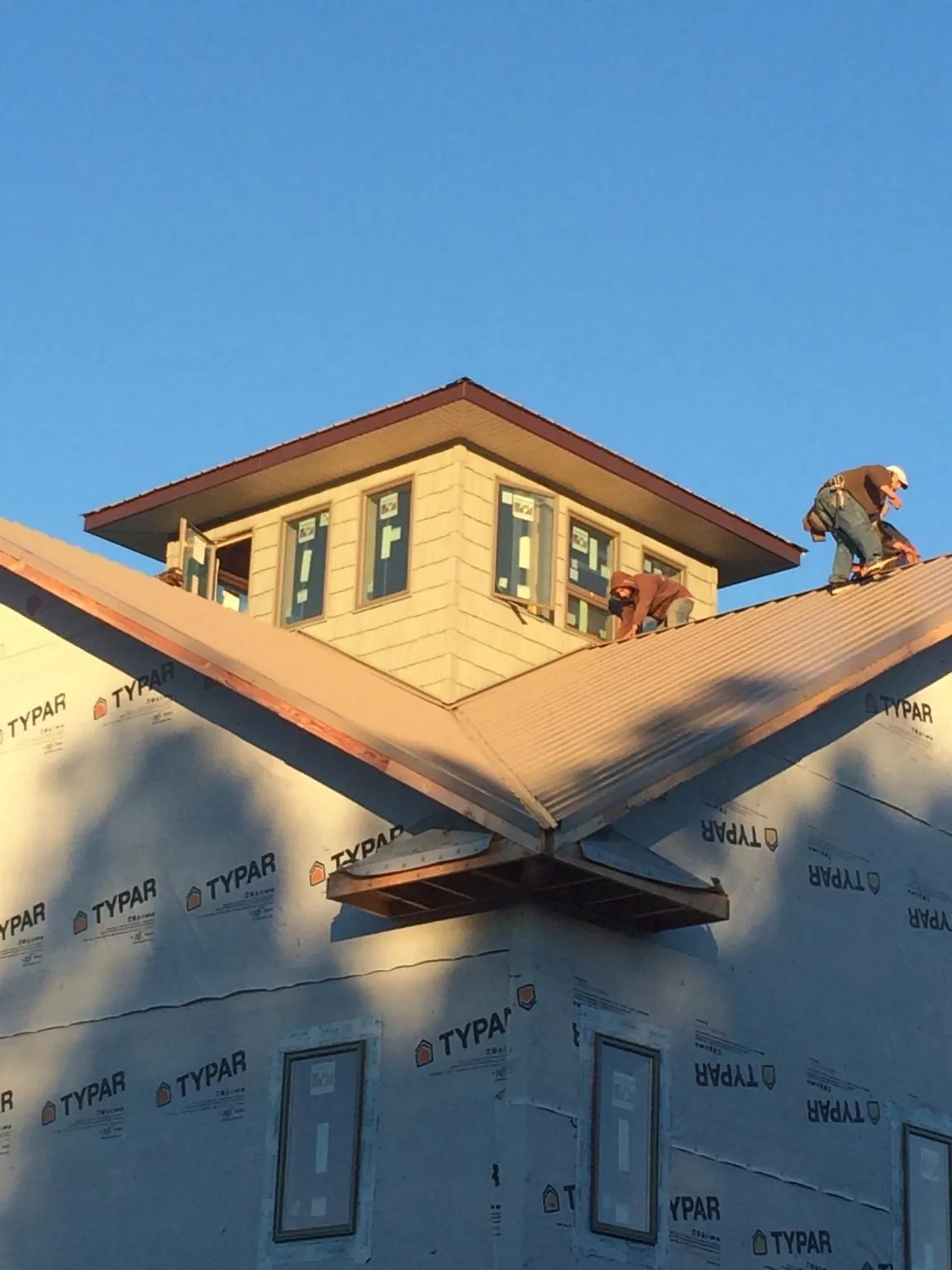 Roofers working around a rooftop cupola on a new metal roof at sunset — Roof Waterproofing in Woodstock Valley by Roofing Brothers